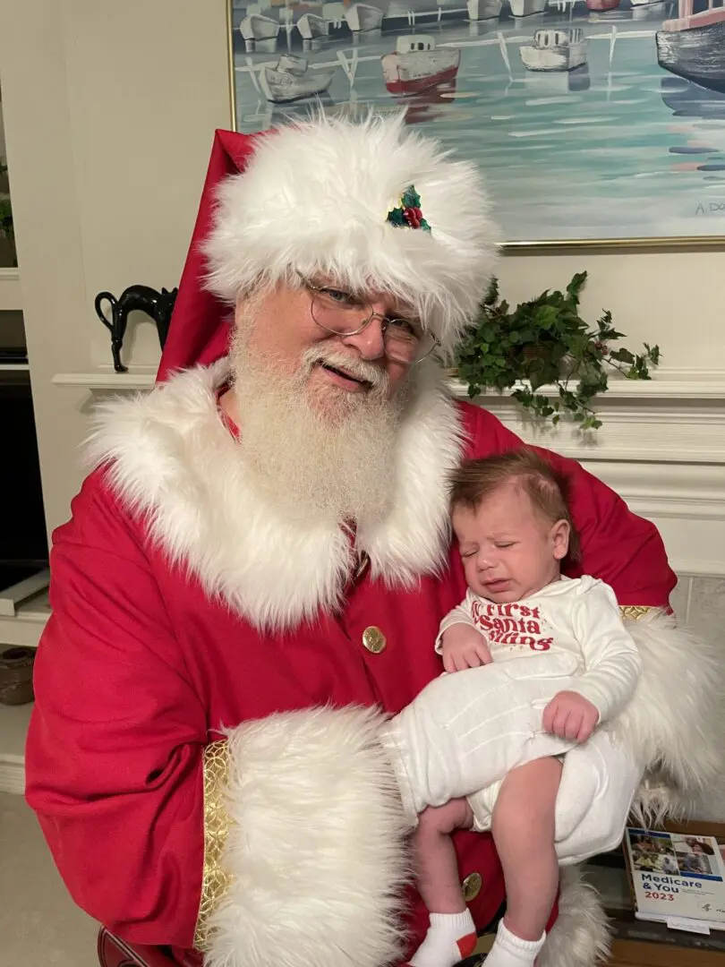 A man dressed as santa claus holding a baby