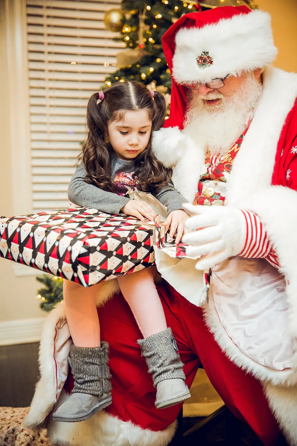 A little girl sitting on santa 's lap with his hands wrapped around him.