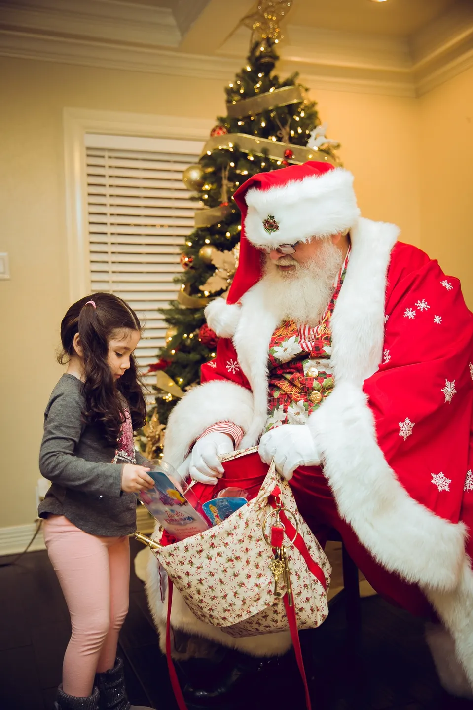 A little girl is handing presents to santa claus.