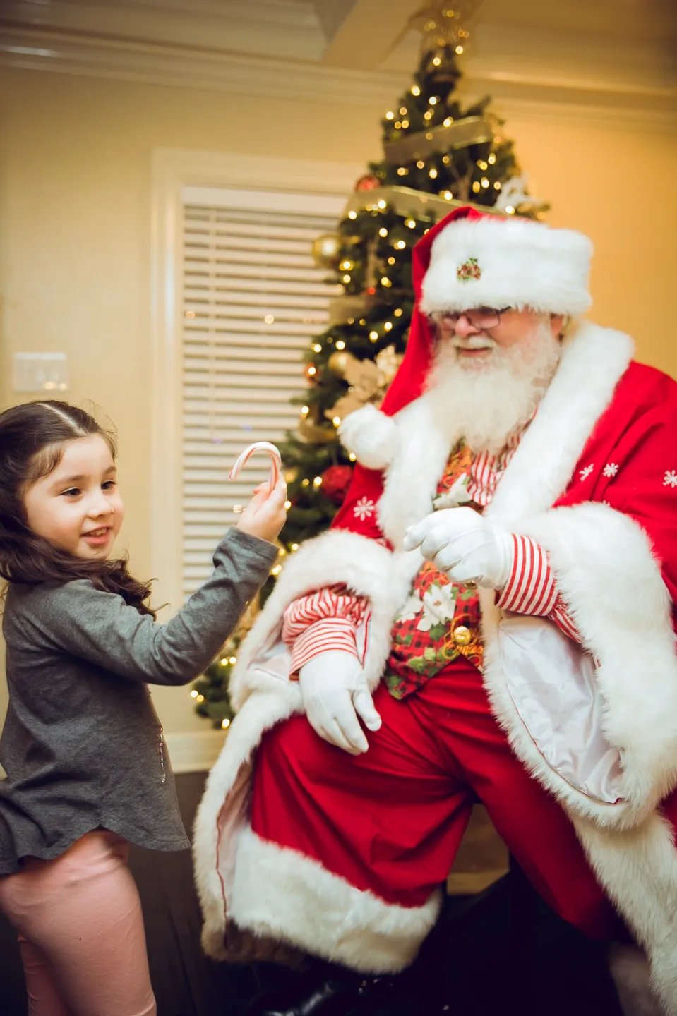 A little girl standing next to santa clause.